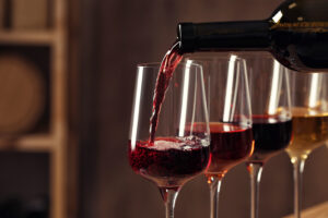 Pouring wine from bottle into glass in cellar, closeup Pouring wine from bottle into glass in cellar, closeup